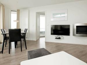 a white living room with a table and a television at One-Bedroom Holiday home in Wendtorf 10 in Wendtorf