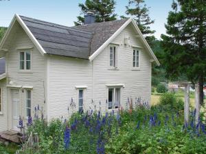 une maison blanche avec des fleurs violettes devant elle dans l'établissement Three-Bedroom Holiday home in Skatvik, à Seljesletta