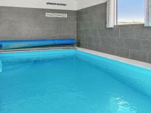 a large swimming pool with blue water in a bathroom at 24 person holiday home in Stege in Stege
