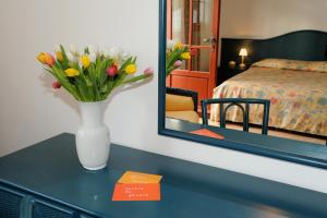 eine Vase mit Blumen auf einem Tisch in einem Hotelzimmer in der Unterkunft La Locanda Azzurra in Sanremo