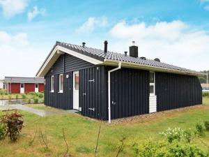 ein schwarzweißes Haus mit Gras in der Unterkunft 6 person holiday home in GROEMITZ in Grömitz