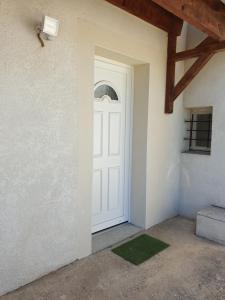 a white door in a room with a green rug at T1 Dans Maison Au Calme in Réalmont