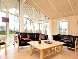 un soggiorno con mobili in pelle nera e un tavolo di 8 person holiday home in Sj lund a Hejls