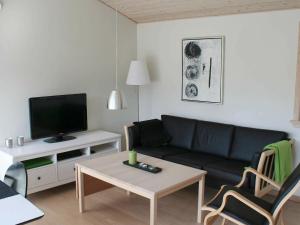 グドイェムにある6 person holiday home in Gudhjemのリビングルーム(黒いソファ、テレビ付)