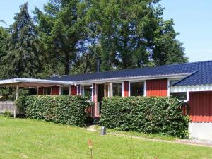 a red house with bushes in front of it at 4 person holiday home in Vordingborg-By Traum in Vordingborg
