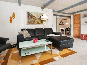 Hejlsにある4 person holiday home in Hejlsのリビングルーム(黒い革張りのソファ、テーブル付)