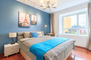 Un dormitorio con una cama con paredes azules y una ventana en Baoding Jingxiu·Beiguo Shopping Mall·, en Baoding