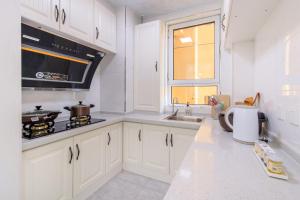 a white kitchen with a stove and a sink at Baoding Lianchi·Baoding East Station· in Baoding