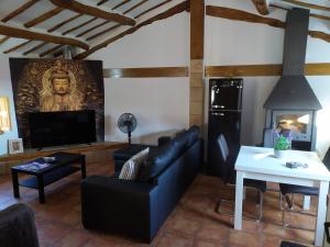 un soggiorno con un divano nero e una TV di CASA VILLAVERDE DE RIOJA a Villaverde de Rioja