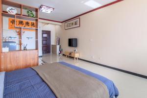 een slaapkamer met een bed en een tv aan de muur bij Baoding Lianchi·Baoding East Station· in Baoding