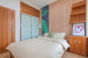 a bedroom with a white bed and wooden cabinets at [Roader] Wuhan Jiang'an District · Sanyang Road in Wuhan