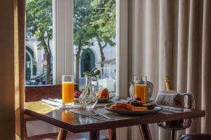 a table with a plate of fruit and two glasses of orange juice at Lisboa Carmo Hotel in Lisbon