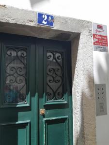 uma porta verde com duas janelas num edifício em my lovely Alfama's studios em Lisboa