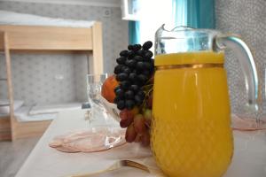 a jug of orange juice and a bowl of fruit on a table at Babulya House in Gyumri