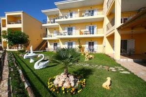 a large apartment building with a garden in front of it at Alexios Apartments in Perdika