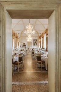 una sala da pranzo con tavoli, sedie e lampadario a braccio di Relais Castello Bevilacqua a Bevilacqua