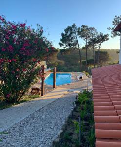 - une piscine à côté d'une maison ornée de fleurs roses dans l'établissement Casa do Moinho de Baixo, à Sesimbra
