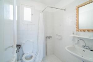 a white bathroom with a toilet and a sink at Alkionides Studios in Koufonisia