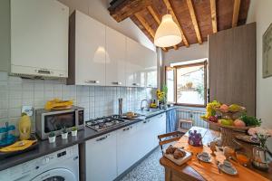 Oltrarno Apartment في فلورنسا: مطبخ فيه دواليب بيضاء وطاولة فيه