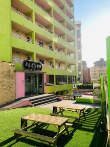 un grupo de mesas de picnic frente a un edificio en Now Benidorm, en Benidorm