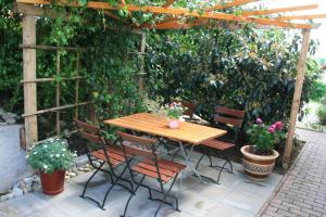 a wooden table and chairs under a pergola with plants at Ferienwohnung am Rotdornweg in Heiligenstadt