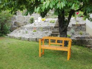 a wooden bench sitting in the grass under a tree at Ferienwohnung am Rotdornweg in Heiligenstadt