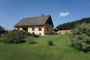 ein großes Haus auf einem grasbewachsenen Feld mit Bäumen in der Unterkunft Ferienwohnung Penning in Oberfellendorf