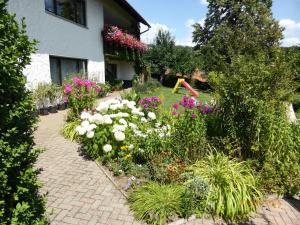 un jardín con flores y un parque infantil frente a una casa en Ferienwohnung Kunze en Obernsees