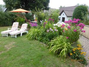 einen Garten mit zwei Stühlen, Blumen und einem Sonnenschirm in der Unterkunft Ferienwohnung Kunze in Obernsees