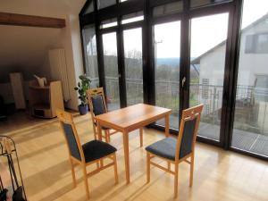 a table and chairs in a room with a balcony at Ferienwohnung Küpfer in Gräfenberg