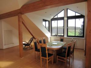 een eetkamer met een tafel, stoelen en ramen bij Ferienwohnung Küpfer in Gräfenberg