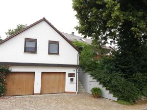 Biały dom z dwoma drzwiami garażowymi w obiekcie Ferienwohnung Kunze w mieście Obernsees