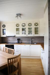 cocina con armarios blancos y mesa de madera en Myrkdalen Resort Nedre Byggardslii apartment, en Vossestrand