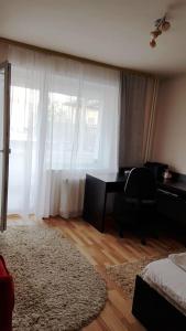 a bedroom with a desk and a chair in front of a window at Apartament Gia in Oradea