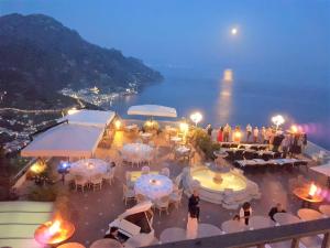 un grupo de mesas y sillas con vistas al océano en Hotel Villa Fraulo, en Ravello