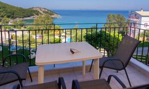 a table and chairs on a balcony with a view of the ocean at Alexios Apartments in Perdika