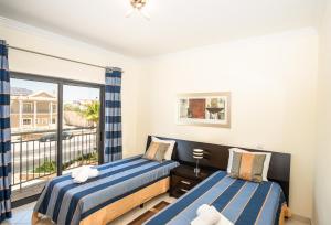 a bedroom with two beds and a balcony at Jardins de Pêra in Pêra