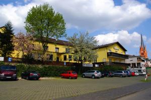 梅因塔爾的住宿－Hotel-Restaurant Zur Mainlust，一座黄色的建筑,汽车停在停车场