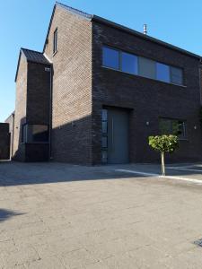 a brick building with a garage and a tree in front at La Maison de Marie in Borgloon