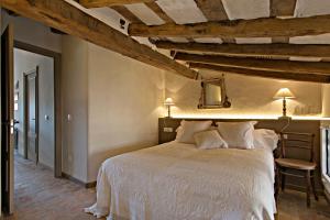 a bedroom with a white bed in a room with wooden ceilings at El Jardinet de Sant Esteve in Olot