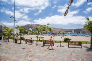 een vrouw die op een stoep loopt bij een strand bij Sunny studio Flat in Los Cristianos