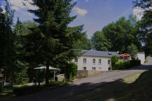 un edificio blanco con árboles al lado de una carretera en Maison gîte à Vire Normandie (Les Vaux de Vire), en Vire