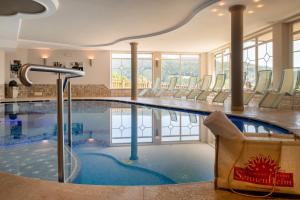 a swimming pool in a hotel with chairs around it at Hotel Sonnenheim in Avelengo