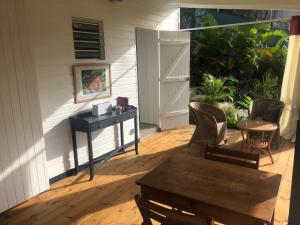 un porche con sillas, una mesa y un taburete en Agréable appartement à 2 pas des plages, en Le Gosier