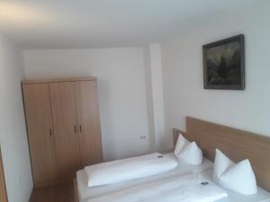 ein Schlafzimmer mit einem Bett und einem Schrank mit Kissen in der Unterkunft Hotel Garni Post in Grainau