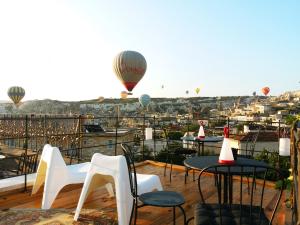 eine Terrasse mit Tischen, Stühlen und Heißluftballons in der Unterkunft Karadut Cave Hotel in Goreme