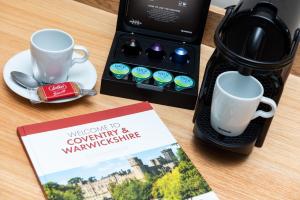 een koffiezetapparaat en een boek op een tafel met een koffiemok bij Brandon Hall Hotel & Spa Warwickshire in Brandon