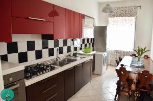 een keuken met rode kasten en een wastafel bij BICIaMICI Apartments in Scafati