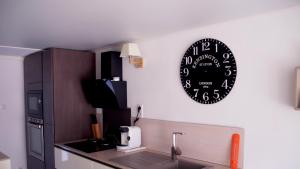 a black clock on a wall above a kitchen counter at T2 climatisé baignoire terrasse Jacuzzi Piscine Sauna in Launaguet