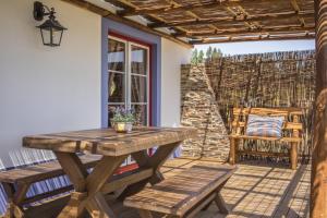a wooden table and benches on a patio with a window at Monte da Boavista in São Teotónio